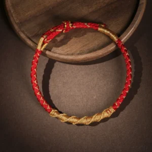 Two-tone red and gold Tibetan protection bracelet with adjustable sliding knot, top-three quarter product photography