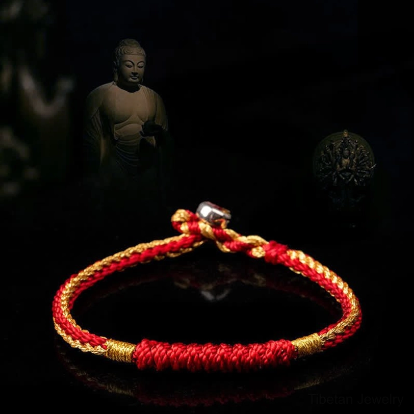 Red and gold Tibetan braided luck string bracelet, flat lay with twisted rope weaving and silver buckle detail