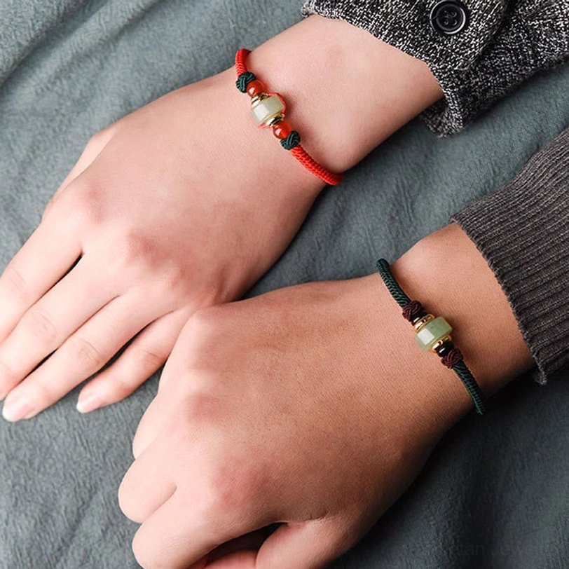 Single Tibetan red braid luck bracelet on wrist featuring green aventurine barrel bead and agate accents