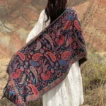 Tibetan paisley tassel shawl in red - back view outdoor mountain scene showing handwoven ethnic embroidered pattern