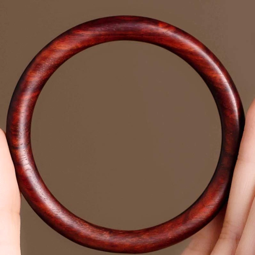 Tibetan protection bracelet made from red sandalwood showing deep reddish-brown color and uniform round profile with smooth finish