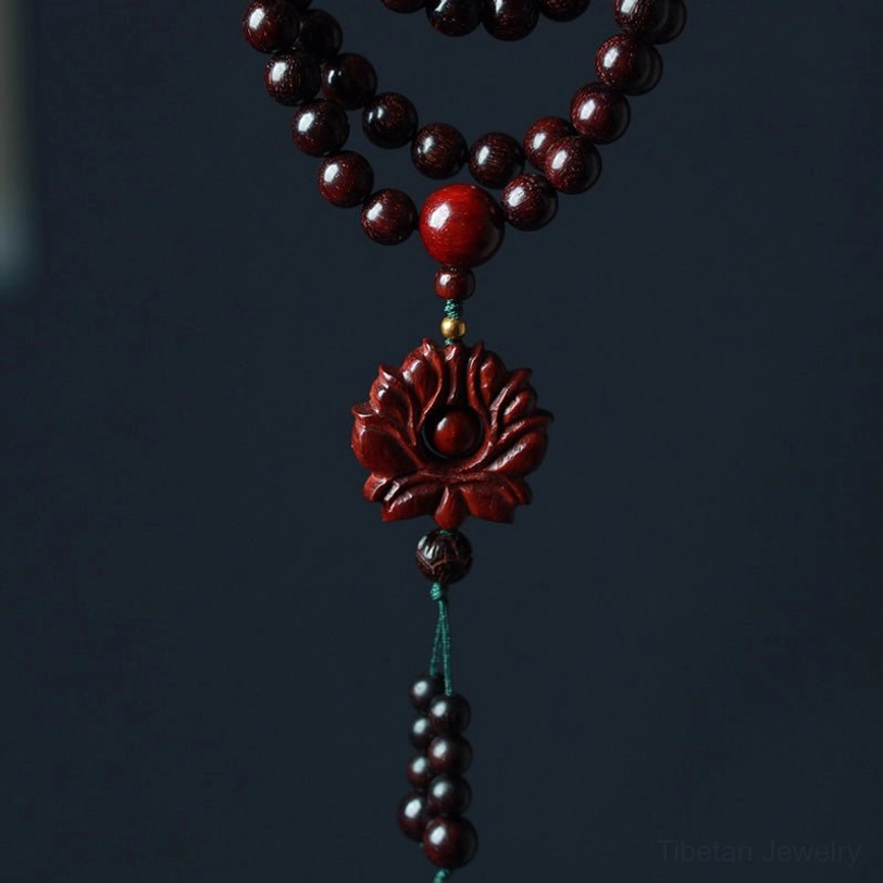 Full red sandalwood lotus mala centered flat lay with central red spacer bead and carved lotus tassel pendant