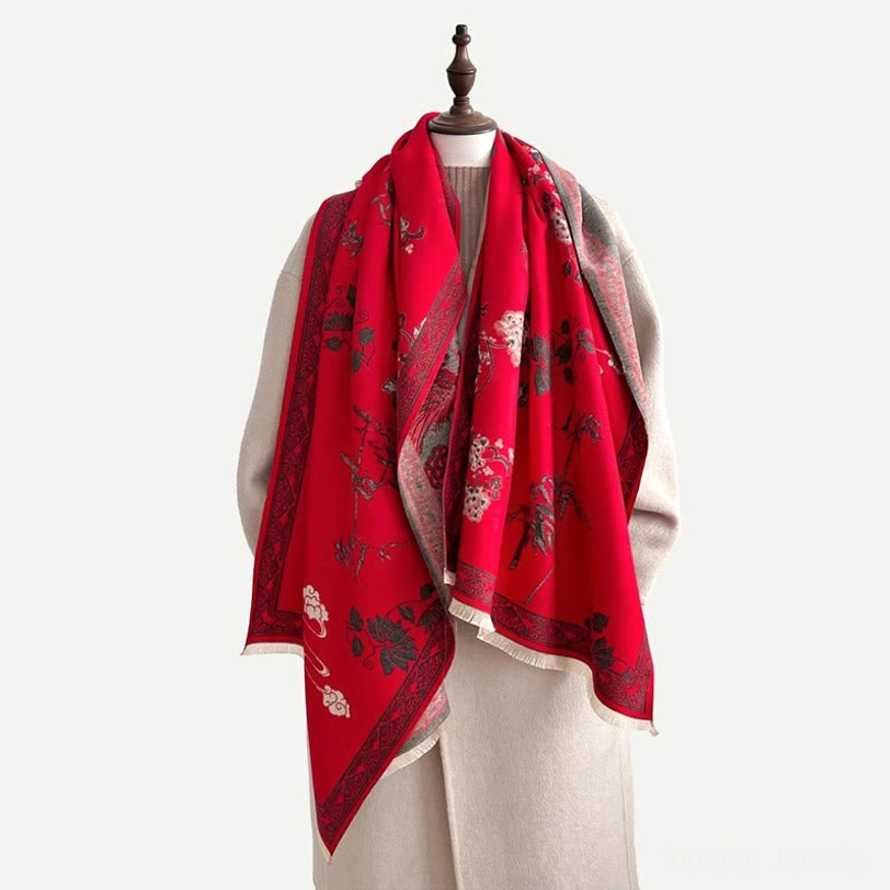 Red Tibetan scarf draped on mannequin shoulder showing partial floral print and woven texture