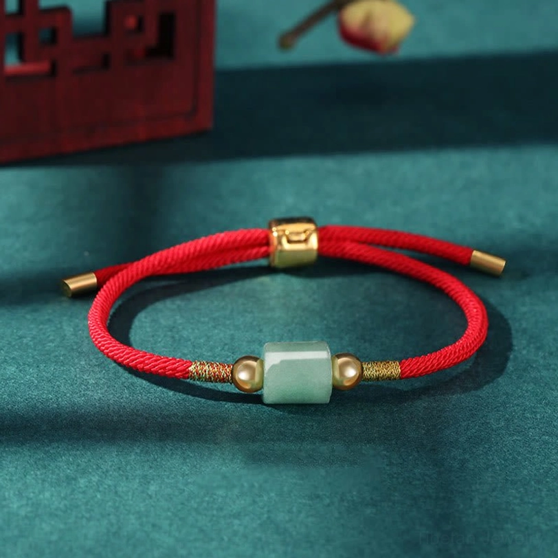 Single red Tibetan woven protection bracelet with light green barrel bead and gold decorative accents on teal retro desktop