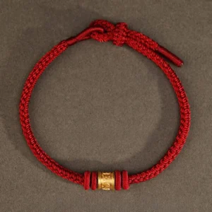 Overhead view of sacred red string bracelet with mantra bead, Tibetan spiritual protection jewelry