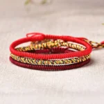 Tibetan red string bracelet set of three handwoven designs flat lay on natural linen fabric background