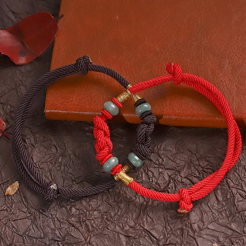 Red string jade bracelet with decorative knot worn on wrist in lifestyle setting