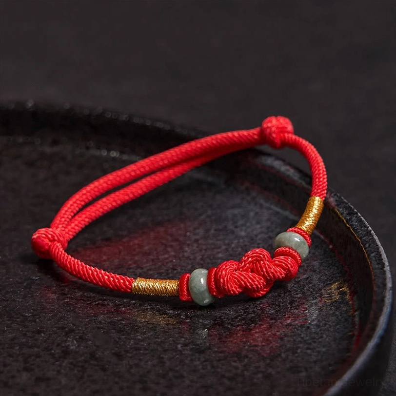Side profile of red cord jade bracelet with gold accents and braided decorative knot detail