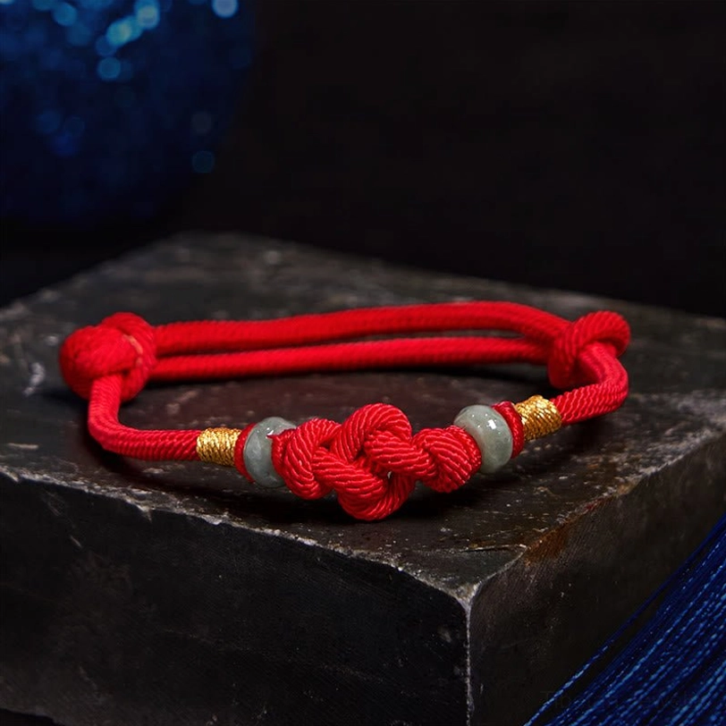 Top-down view of red string jade couple bracelet showing decorative knot and jade stone accents