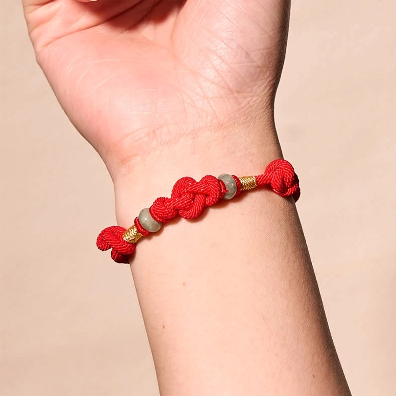 Side view of red string jade bracelet worn on wrist showing gold accents and jade beads