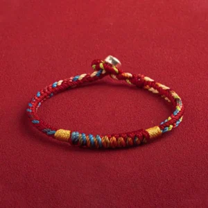 Handcrafted red and multicolor Tibetan protection bracelet with silver accents, three-quarter side view showcasing braided weaving