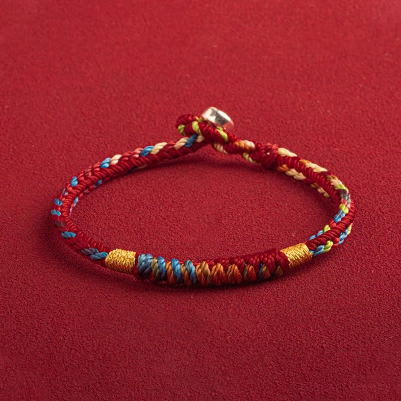 Handcrafted red and multicolor Tibetan protection bracelet with silver accents, three-quarter side view showcasing braided weaving