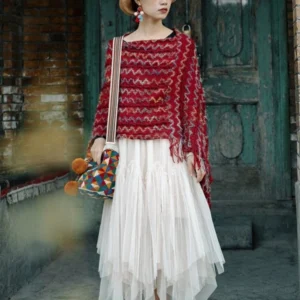 Red tibetan striped tassel shawl with zigzag multicolor weave and fuzzy knit fabric worn as ethnic poncho in front of vintage wooden door