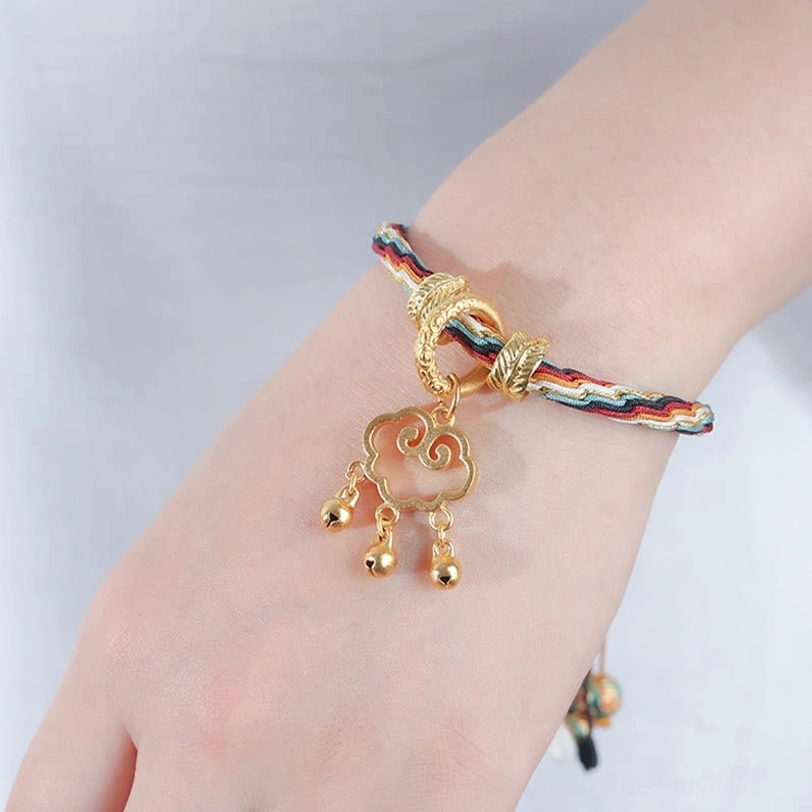 Multicolor braided reincarnation bracelet on hand back view with gold decorative buckles and cloud lock bells