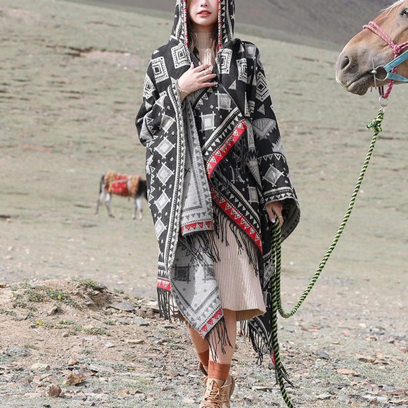 Reversible Tibetan hooded poncho in grey and black geometric print with fringe trim, paired with casual dress