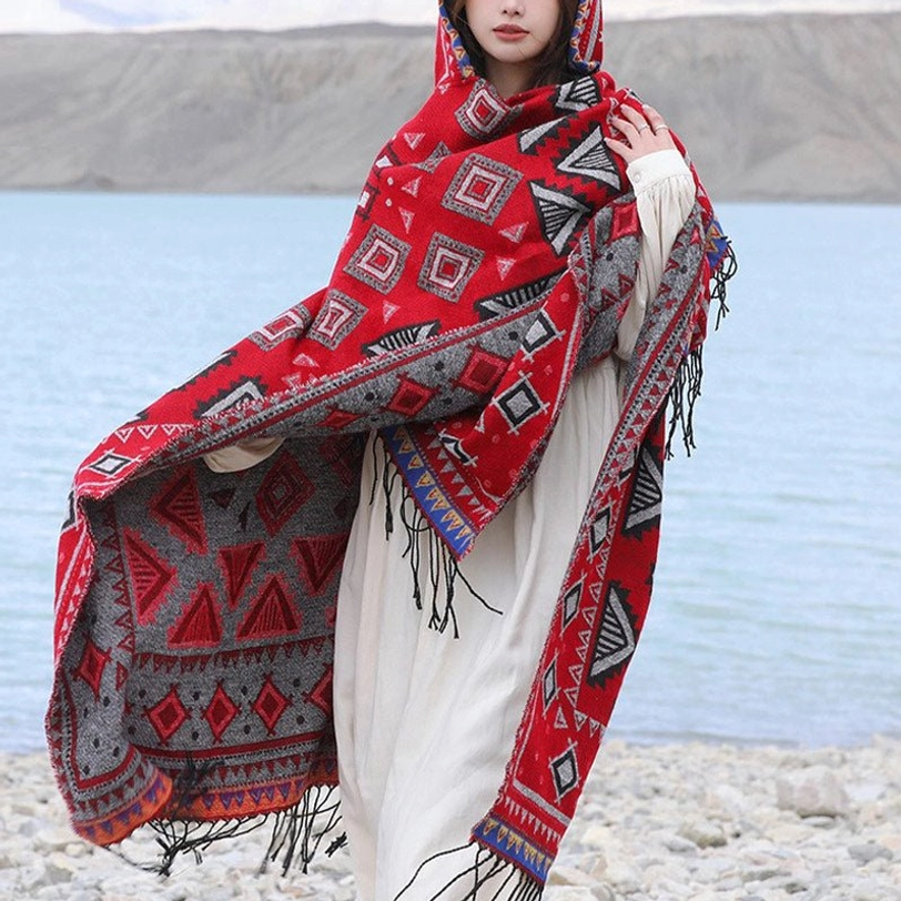Reversible red and grey Tibetan poncho with geometric pattern and fringe edges, worn over long dress