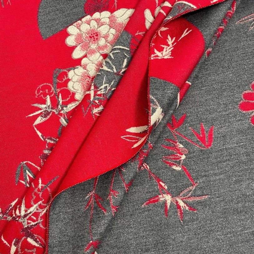 Close-up detail of red and grey reversible Tibetan scarf showing bamboo peony motifs and textured weave