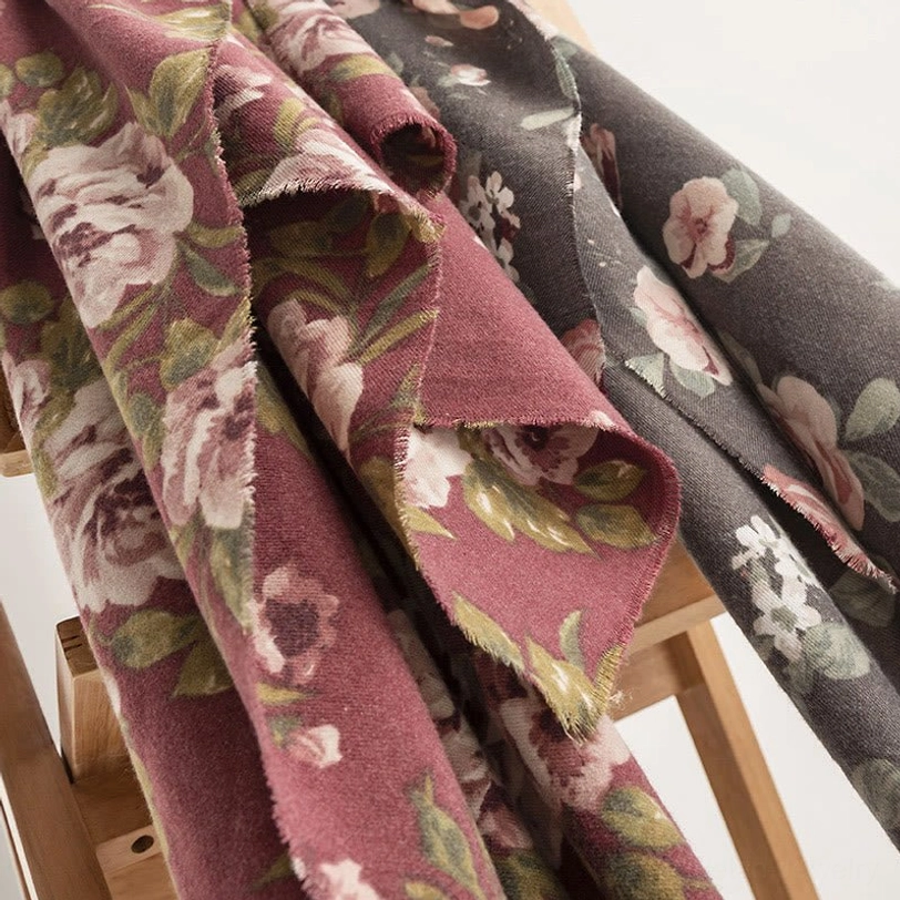 Tibetan rose shawls folded flat lay on wooden stool showing two colorways and soft fuzzy fabric texture