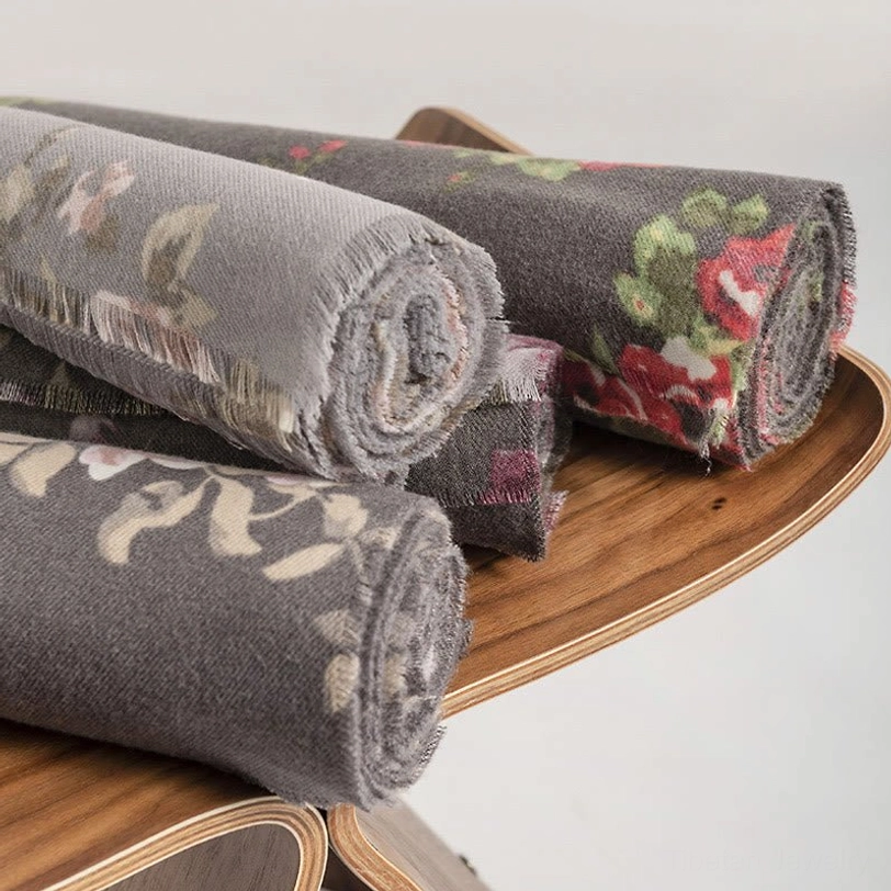 Rolled Tibetan rose shawls displaying soft cozy fabric texture and frayed edges on wooden tray