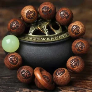 Tibetan rosewood tiger engraved protection bracelet top-down view showing hand-carved sacred script beads and luminous green spacer bead on metal censer