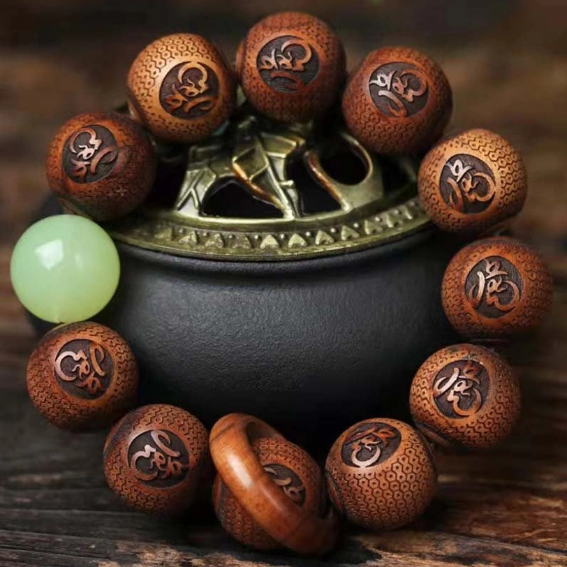 Tibetan rosewood tiger engraved protection bracelet top-down view showing hand-carved sacred script beads and luminous green spacer bead on metal censer