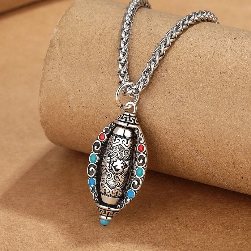 Tibetan mantra pendant necklace side profile showing antique silver finish wheat-link chain and rotating barrel design with embedded gemstones