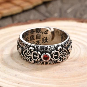 Front view of Tibetan Buddhist copper ring with central ruby gem and embossed traditional spiritual patterns open adjustable band