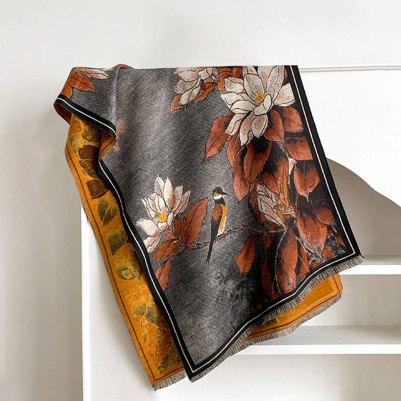 Dark grey Tibetan scarf with rust red magnolia flower and bird motif displayed on shelf - flat lay