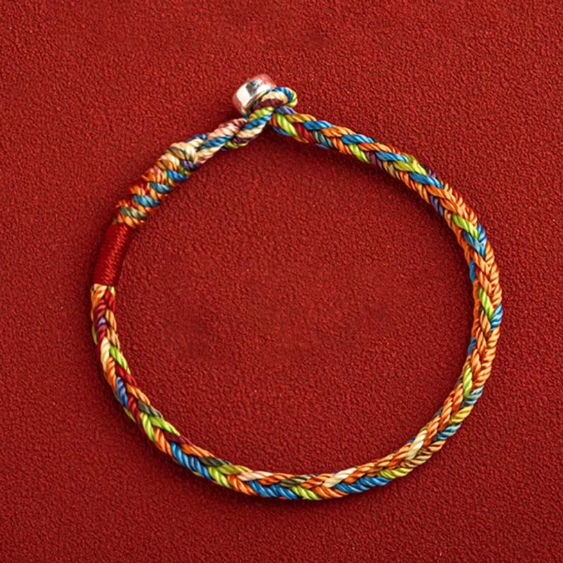 Sacred King Kong knot multicolored bracelet high angle flat lay on red fabric with red accent cord near clasp