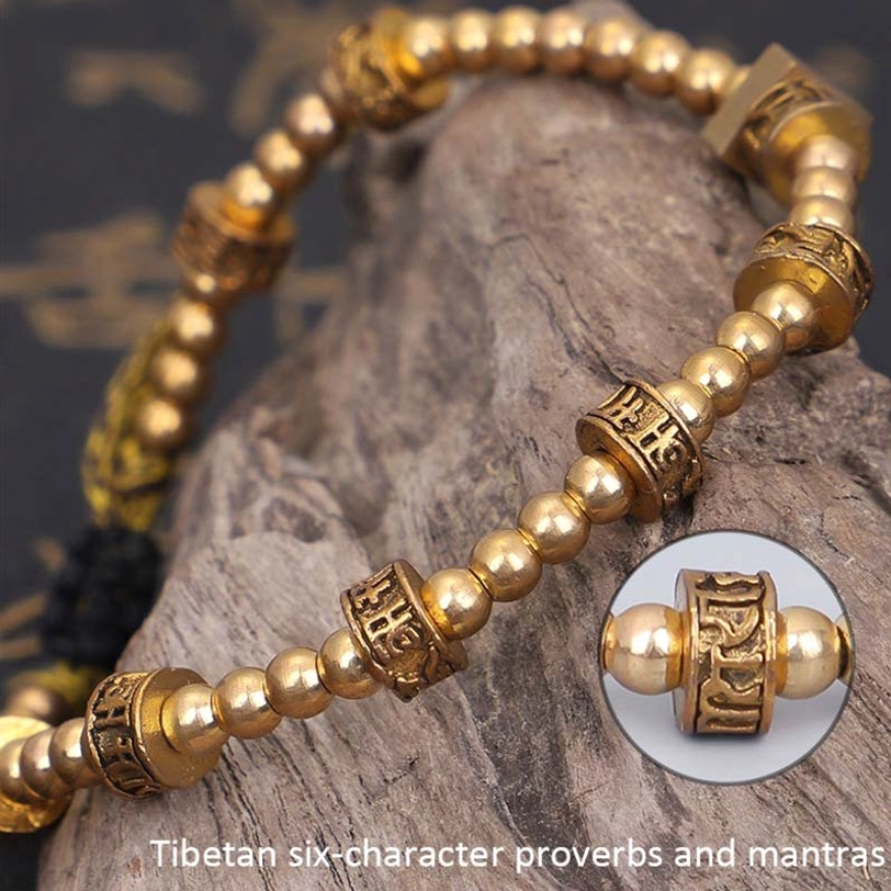 Detailed close-up of Tibetan mantra bead with embossed sacred script on wooden stone background