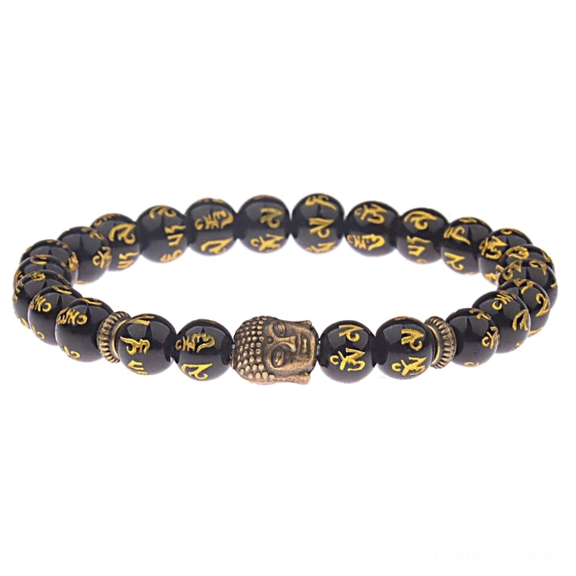 Tibetan Buddhist mantra bracelet with silver Buddha charm and black beads featuring gold Sanskrit mantras on textured wooden surface