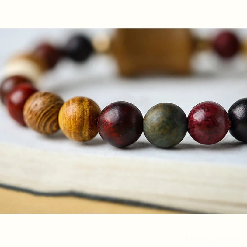 Tibetan sandalwood bracelet beads in shallow focus showing mixed natural wood colors and textures with carved focal bead in background