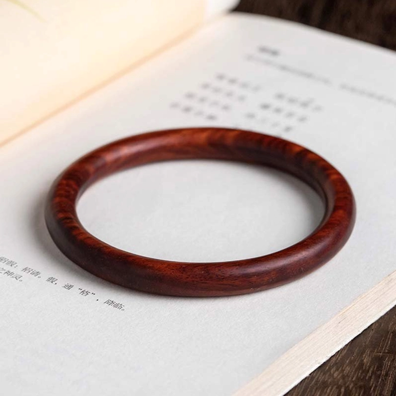 Tibetan red sandalwood wood bracelet bangle displaying glossy polished surface and authentic natural wood grain texture