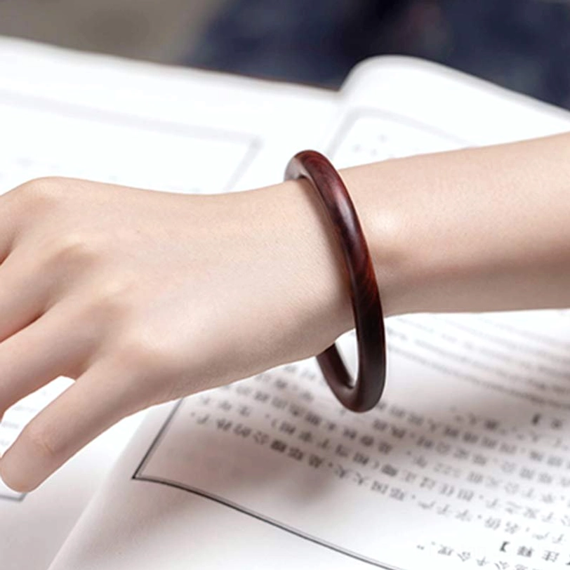 Handcrafted Tibetan wood protection bracelet on wrist displaying smooth polished surface and natural wood characteristics