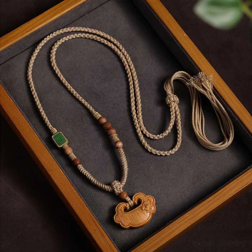 Tibetan sandalwood lock charm necklace flat lay on wooden tray showing braided cord, wooden beads, and traditional ruyi pendant