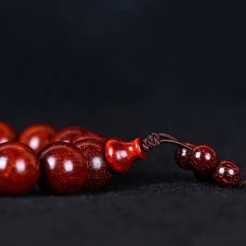 Hand holding Tibetan red sandalwood mala bracelet during meditation practice, showing comfortable bead size