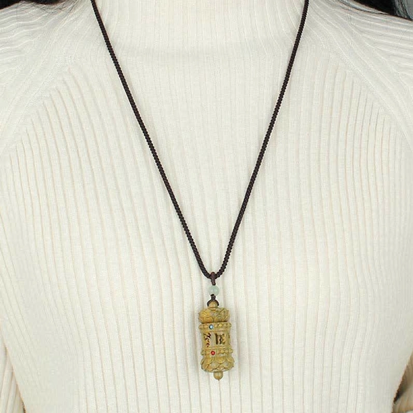 Tibetan sandalwood pendant necklace worn on person over white ribbed knit sweater, showing natural hanging posture and scale