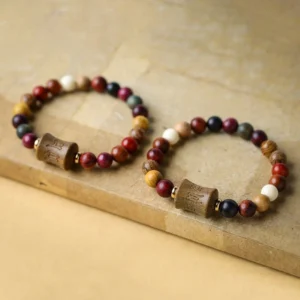 Two matching handmade Tibetan sandalwood bracelets with Om Mani Padme Hum carving displayed together on wooden desk background