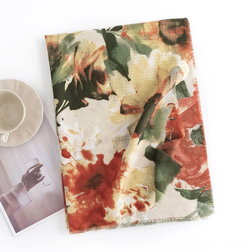 Beige Tibetan vintage floral scarf with rust and green watercolor flowers displayed on tabletop with coffee cup