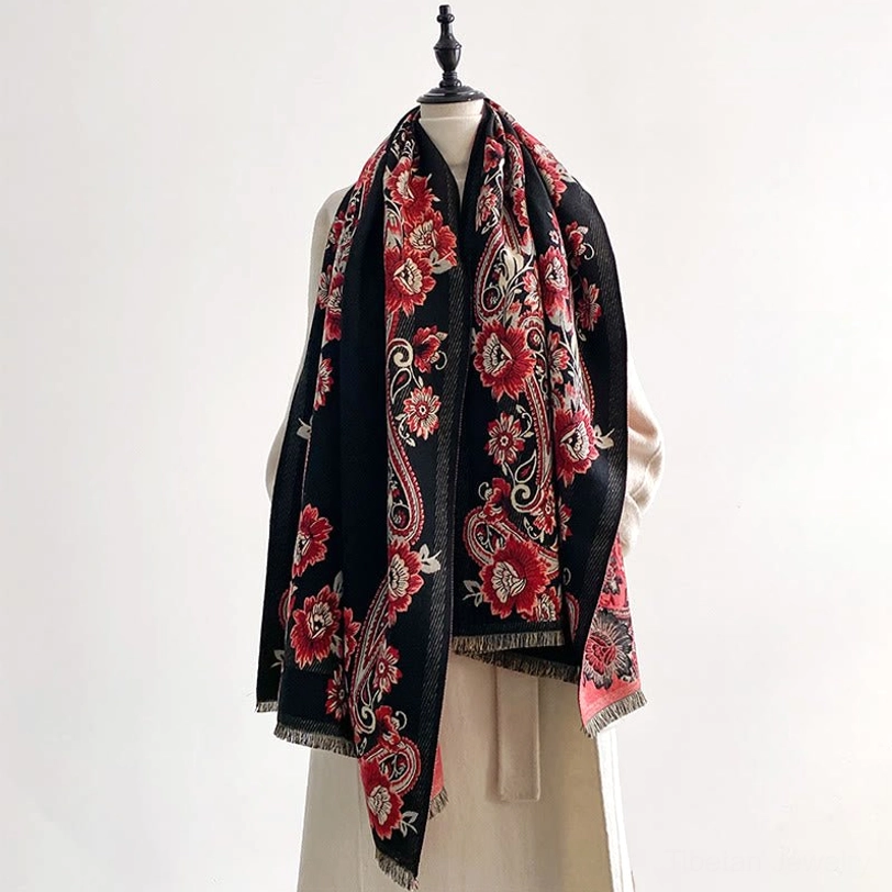 Tibetan scarf with black base and red blue floral paisley patterns, mannequin display showing draped styling and fringe edges