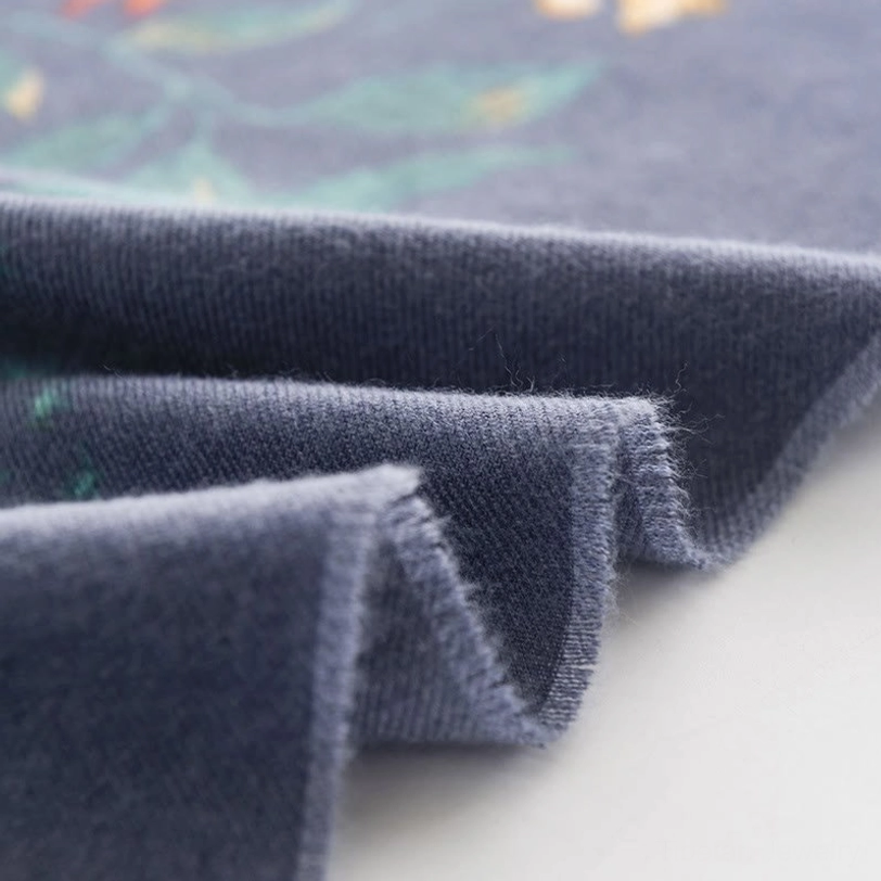 Folded Tibetan scarf fabric close-up displaying frayed raw edges and soft fuzzy texture on muted blue base color