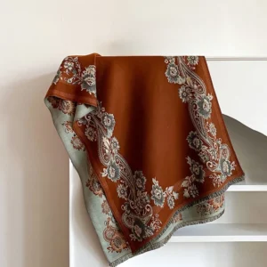 Handwoven Tibetan scarf with brown base and blue-gray paisley floral trim, flat lay shelf display showcasing soft woven fabric texture