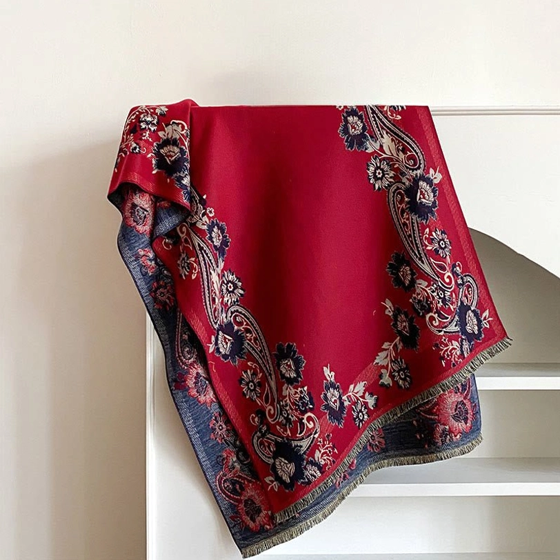 Burgundy Tibetan handwoven scarf with navy paisley floral trim and blue-gray reverse, flat lay shelf presentation with fringed hem