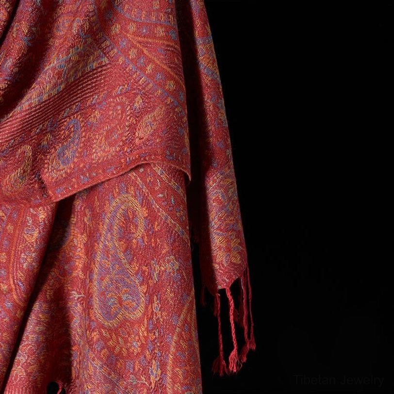 Extreme close-up of Tibetan scarf fabric, highlighting ribbed edge and detailed paisley pattern weave
