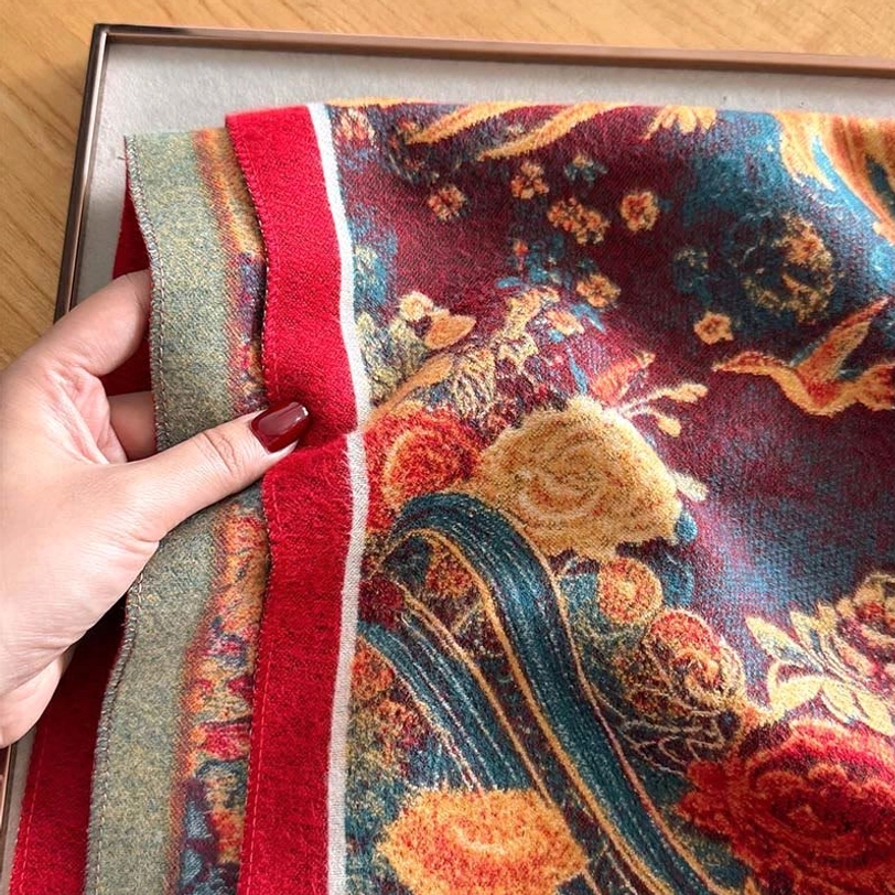 Close-up detail of Tibetan scarf fabric texture showing layered edge trims plush pile and floral print with red accent band
