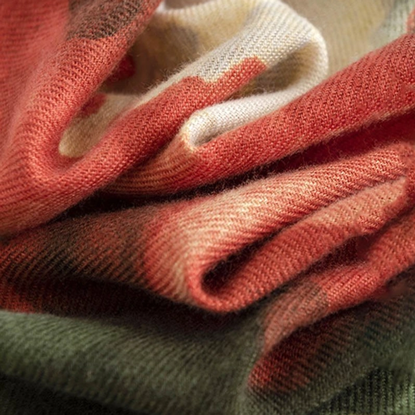 Close-up of Tibetan ink scarf fabric texture showing soft brushed woven material in rust green and cream tones