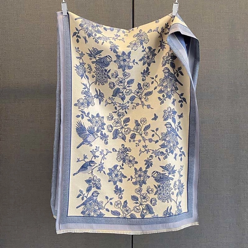 Blue-style Tibetan floral and bird scarf with blue-grey border on beige flat hanging presentation