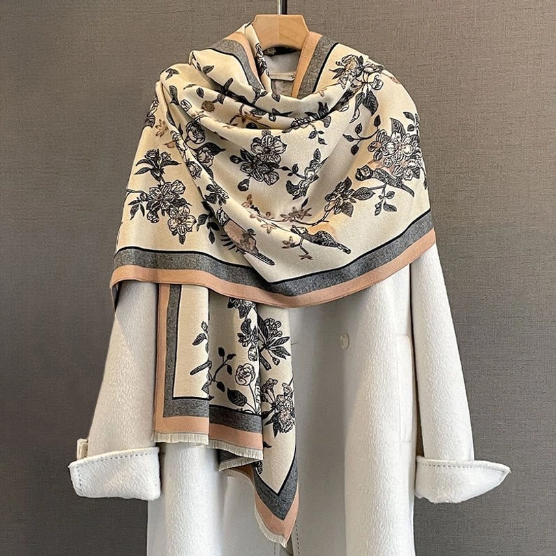 Black floral bird Tibetan scarf with brown-grey trim draped over white coat studio styling
