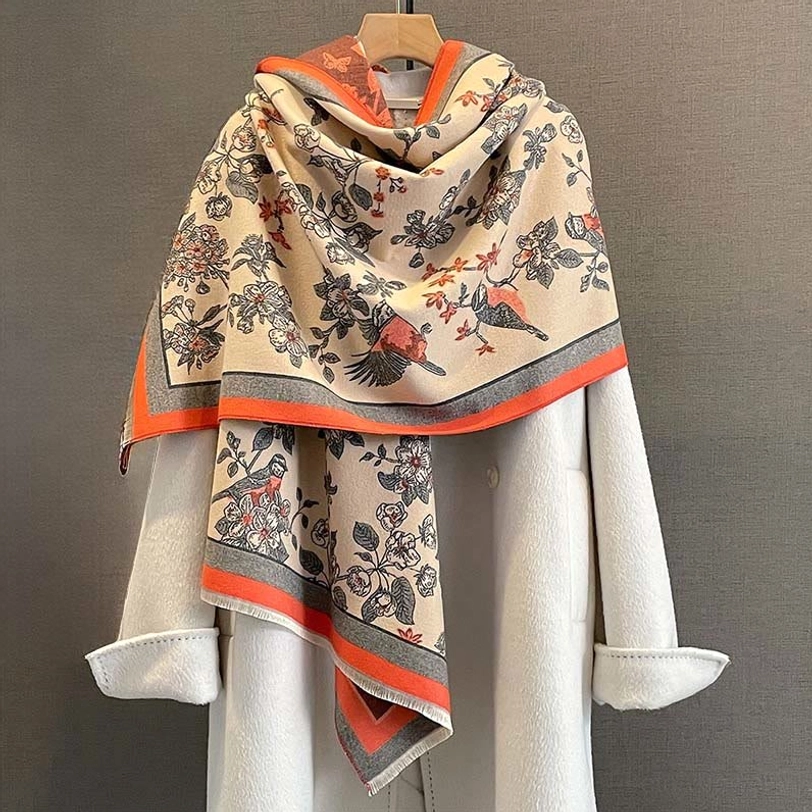 Tibetan floral bird printed scarf shawl in orange-red beige draped over white coat, front view studio photo
