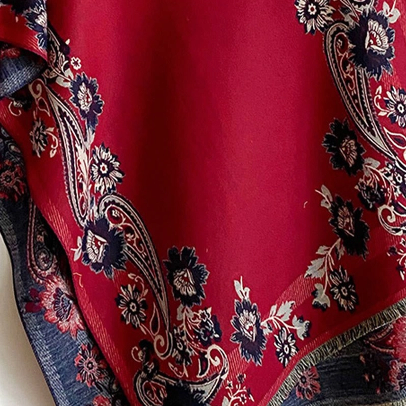 Close-up macro view of Tibetan scarf pattern featuring burgundy base with navy and white paisley floral motifs and jacquard woven texture